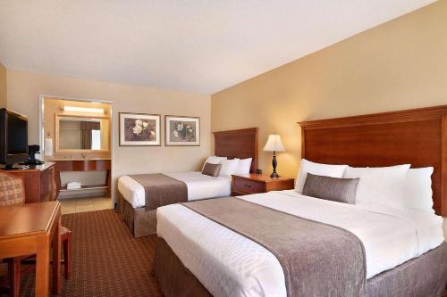 a hotel room with two beds and a desk at Baymont by Wyndham Culpeper in Culpeper