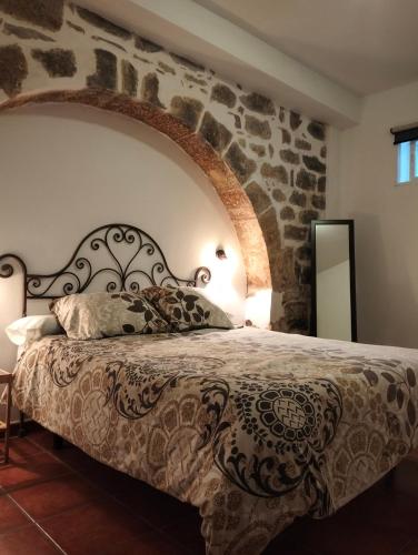 Cama en habitación con pared de piedra en Alojamiento Mercado de Abastos, en Úbeda