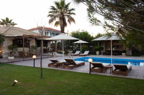 a patio with chairs and umbrellas next to a pool at Iguana Villa in Kalamaki