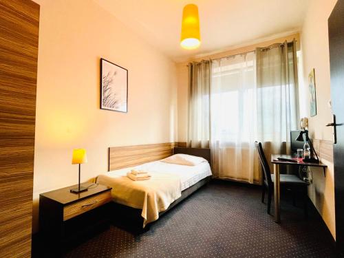 1 dormitorio con cama, escritorio y ventana en Hotel Seven 7, en Kalisz