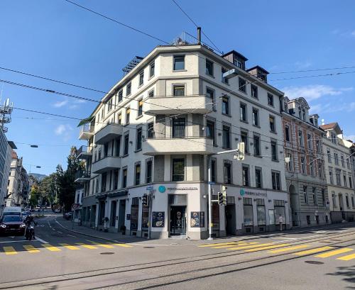 biały budynek na rogu ulicy w obiekcie VISIONAPARTMENTS Brandschenkestrasse w Zurychu