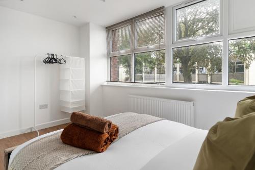 a white bedroom with a bed with two windows at Livestay-Modern Apartments Building in Aylesbury in Buckinghamshire