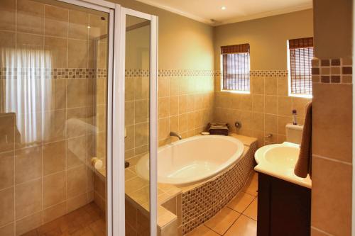 a bathroom with a tub and a shower and a sink at Dalene se Seehuis, Langebaan, 8-sleeper in Langebaan