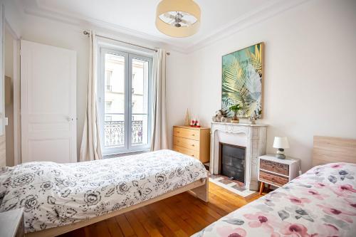 een slaapkamer met 2 bedden en een open haard bij Paris naturellement in Parijs