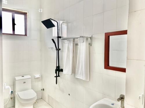 La salle de bains blanche est pourvue de toilettes et d'une fenêtre. dans l'établissement Asili Nyumbani Residence, à Kiwengwa