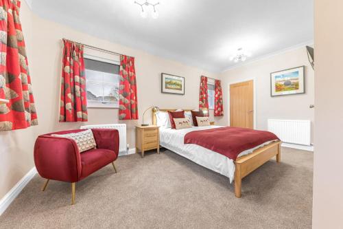 a bedroom with a bed and a red chair at Summerbank Cottage, luxury Lake District holiday home in Coniston in Coniston
