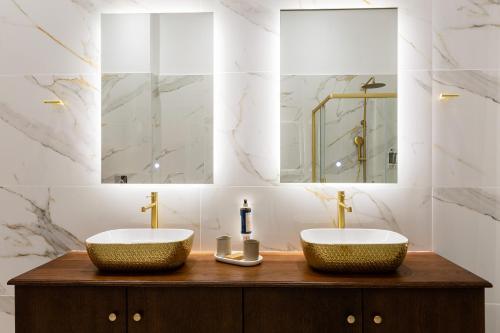 two sinks in a bathroom with marble walls and mirrors at King Othon Boutique Hotel in Nafplio