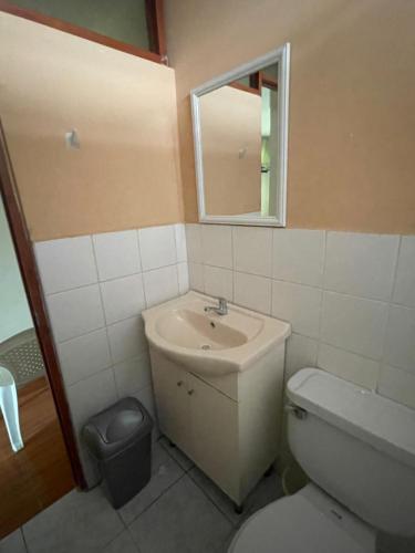 a bathroom with a sink and a toilet and a mirror at Hostal Alborada in Cajamarca