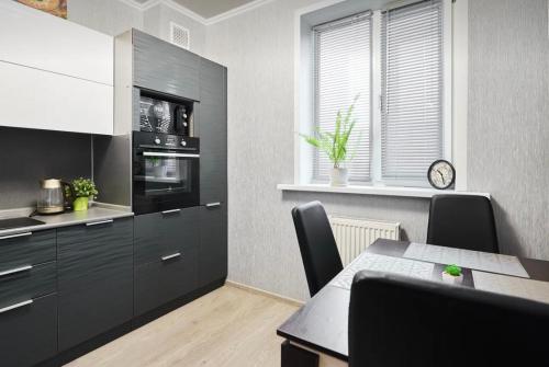 a kitchen with black cabinets and a dining table at VIP apart 703 in Tbilisi City