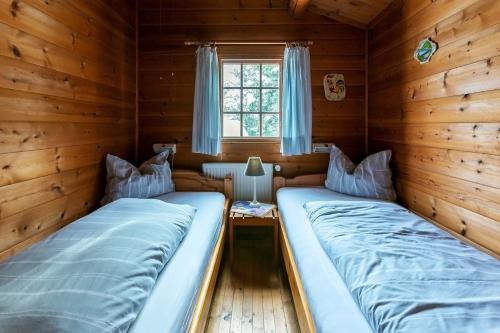 two beds in a log cabin with a window at Blockhaus am Diemelsee in Sudeck