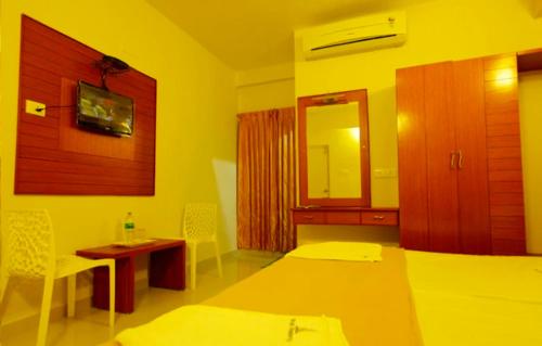 een kamer met 2 bedden, een tafel en een spiegel bij Skylink residency in Chennai