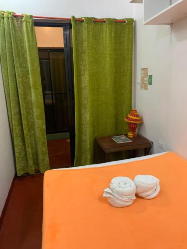 um quarto com uma cama laranja e cortinas verdes em ABBA homestay em General Luna