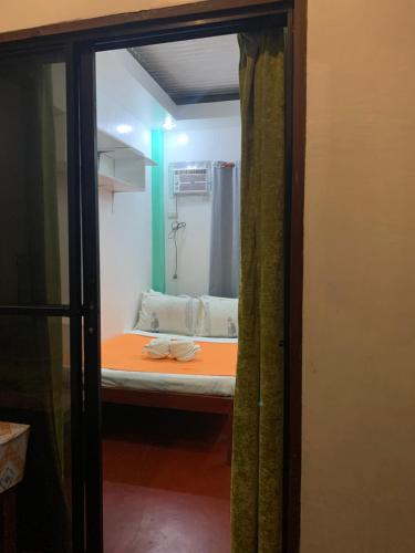 um pequeno quarto com uma cama e um espelho em ABBA homestay em General Luna