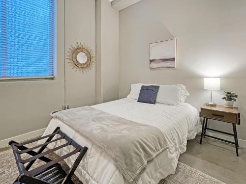 a white bedroom with a bed and a chair at Modern Industrial Apartment With Skywalk in Des Moines