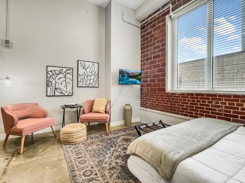 a bedroom with a brick wall and two chairs and a bed at Stunning Downtown Studio With Rooftop Patio in Des Moines