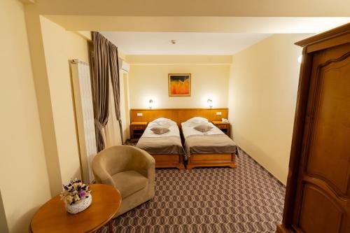 a hotel room with two beds and a chair at Hotel Dorna in Vatra Dornei