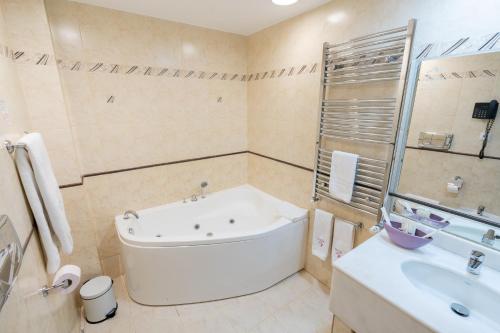 a white bathroom with a tub and a sink at Hotel Dorna in Vatra Dornei