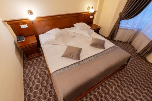 a bed in a hotel room with two pillows on it at Hotel Dorna in Vatra Dornei