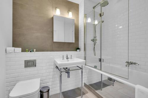 La salle de bains blanche est pourvue d'un lavabo et d'une douche. dans l'établissement Regent's Park Serviced Apartments by MySquare, à Londres