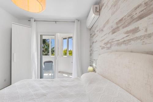 a bedroom with a white bed and a stone wall at Espanatour MENORCA in Dehesa de Campoamor