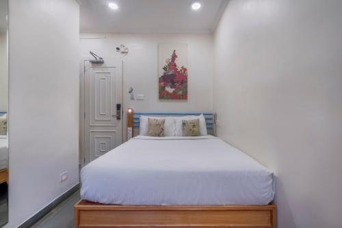 a small bedroom with a bed with white sheets at Hotel Kemps Corner in Mumbai