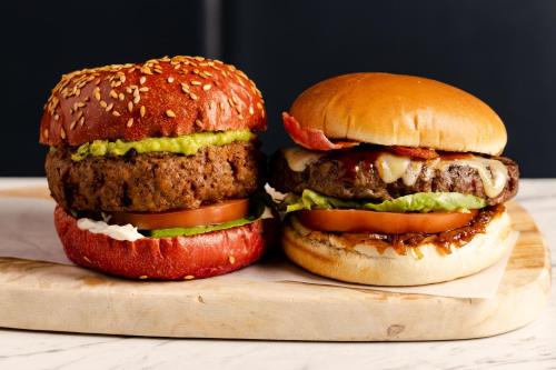 dos hamburguesas sentadas en una tabla de cortar de madera en Leonardo Inn Aberdeen Airport, en Dyce