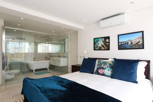 a bedroom with a large bed and a tub and a sink at Modern & Luxurious Seaside Apartment in Cape Town