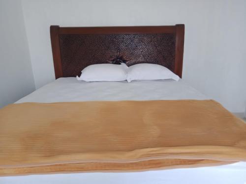 un letto con 2 cuscini bianchi e una testiera in legno di Ratu Balqis Homestay a Banda Aceh
