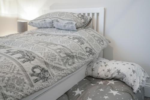 uma cama com um edredão e almofadas em Close to City Centre Stylish and Cosy Home em Belfast
