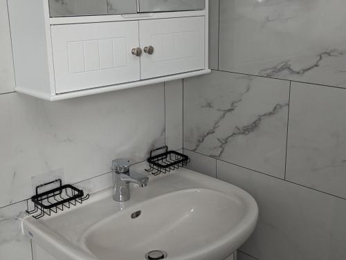 a white bathroom with a sink and a cabinet at Ferienhaus Waldblick im Erzgebirge in Jahnsdorf