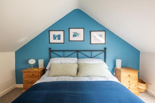 a bedroom with blue walls and a bed with pillows at Riverside Bothy In Heart of Scenic Harbour Village in Solva