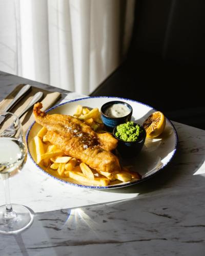 a plate of food with fish and fries on a table at Leonardo Hotel Cheltenham in Cheltenham