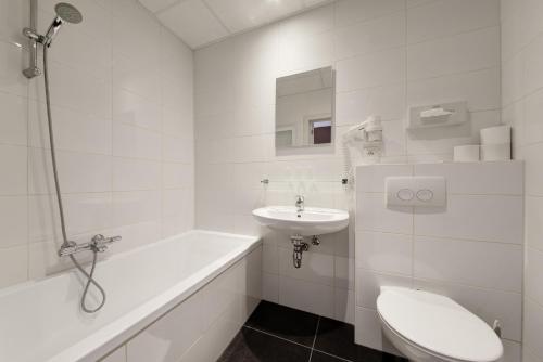 La salle de bains blanche est pourvue de toilettes et d'un lavabo. dans l'établissement Hotel Du Commerce, à Blankenberge