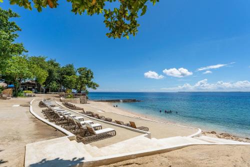 a row of lounge chairs on a beach at OMP 15C-T2, Seaview, Pool & Beach Access, Near Airport, FAST WI-FI, Netflix in Punta Engaño