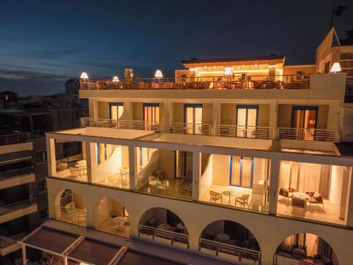 a large white building with a balcony at night at Secret Paradise Hotel & Spa in Nea Kallikrateia