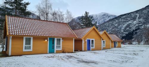 a row of wooden houses with mountains in the background at Lærdal Ferie- og Fritidspark in Lærdalsøyri