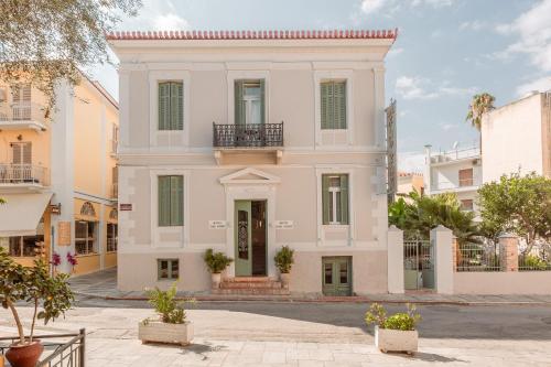 a white house with a balcony on a street at King Othon Boutique Hotel in Nafplio