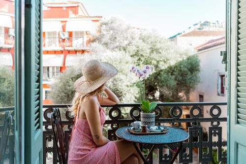 a girl in a hat sitting at a table on a balcony at King Othon Boutique Hotel in Nafplio