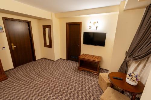 a living room with a television and a couch at Hotel Dorna in Vatra Dornei