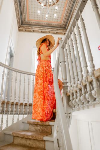 a woman in an orange dress walking down the stairs at King Othon Boutique Hotel in Nafplio