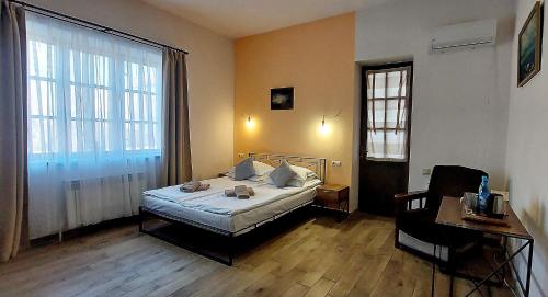 a bedroom with a bed and a desk and two windows at Blur Inn Gallery in Yerevan