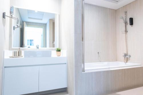 a white bathroom with a sink and a shower at Al Bateen Resdences by HAPPY SEASON JBR in Dubai