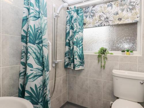 a bathroom with a shower curtain and a toilet at Lavender Cottage in Hailsham