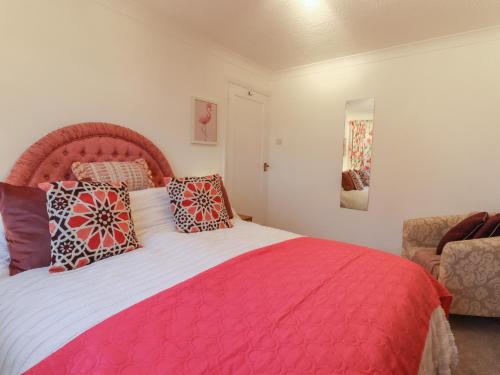 a bedroom with a large pink bed with pillows at Lavender Cottage in Hailsham