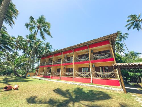 a building with palm trees in front of it at Igarakuê Flat in Japaratinga