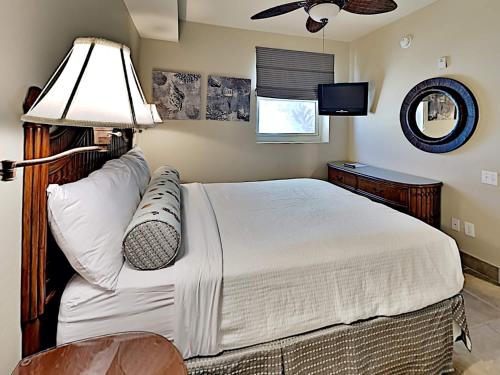 1 dormitorio con 1 cama con lámpara y TV en Beach Club #206A, en Pensacola Beach