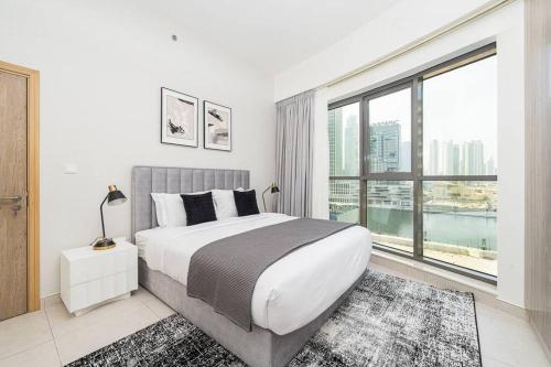 a bedroom with a large bed and a large window at Manzil - 1BR in The Bay with Canal View nr Dubai Mall in Dubai