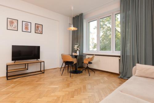 a living room with a television and a table with chairs at Comfortable and Modern Orange Studio in Warsaw by Renters in Warsaw