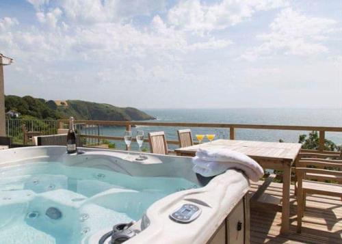 a hot tub on a deck with a view of the ocean at Leonards Cove in Stoke Fleming