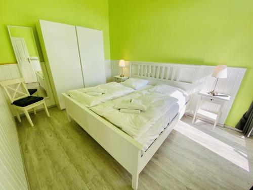 ein Schlafzimmer mit einem weißen Bett und einer grünen Wand in der Unterkunft Berringer, Krabbe, direkt an der Promenade in Warnemünde